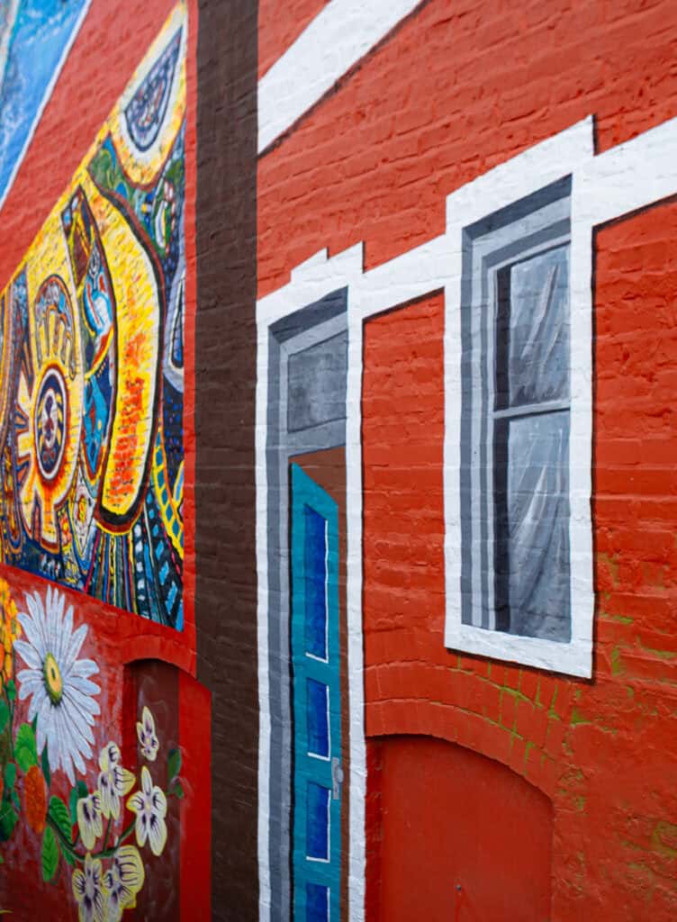 Colorful mural on red brick wall in Chicago's Pilsen neighborhood featuring painted doors and windows